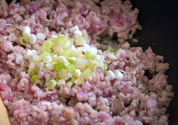 乾鍋，不需放油，將紋肉炒至變色後，放入大蒜、蔥花拌炒。