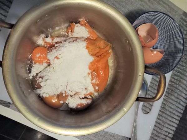 蒸熟的地瓜從電鍋裡取出放涼，接著把剝去皮的地瓜放入鋼鍋，倒入麵粉和雞蛋，用手攪拌均勻。