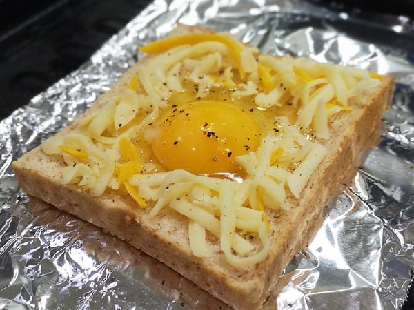 將吐司中心壓一個凹，再把蛋打下去，四周鋪上起司絲，撒上胡椒粉。

吐司不要壓破掉喔，我是用杯子稍微用力壓一下就有個圓形凹槽。