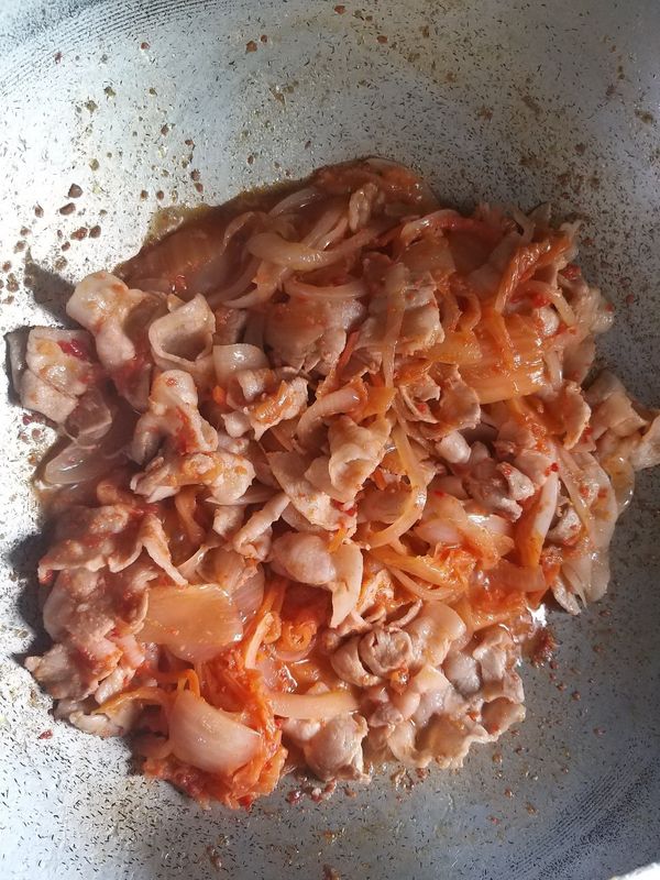 放入明太子風味泡菜及燙過的五花肉片，拌勻後轉小火，拌炒至收汁即可！
（起鍋前可放蔥綠配色，看起來更可口）