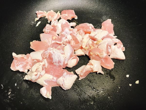 2. 準備一個鍋子倒入些許的油，先將一半蒜丁偏香，再下雞肉拌勻至七分熟盛起備著。