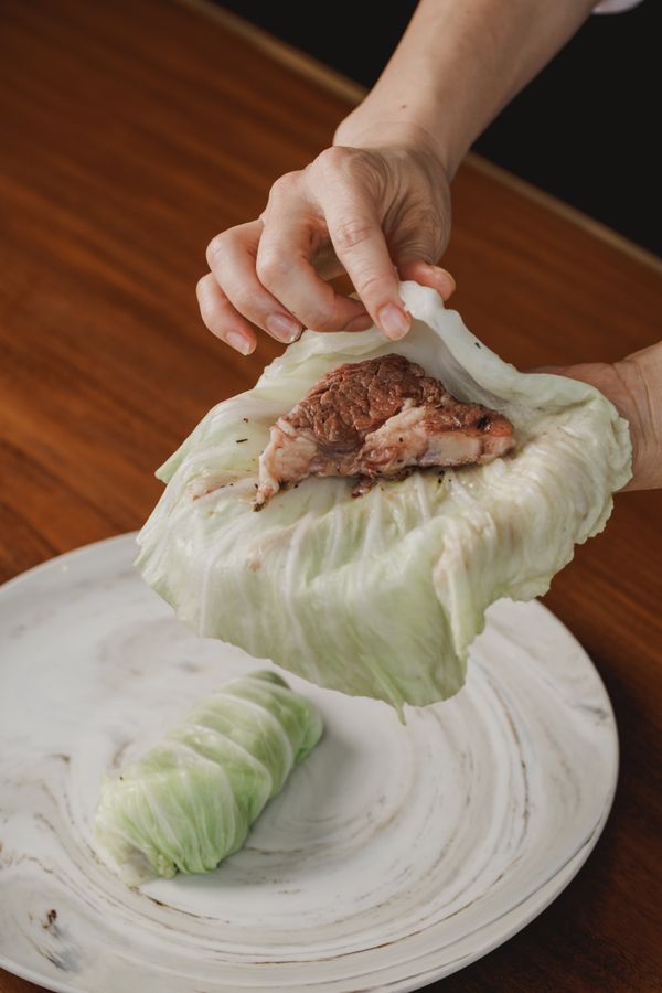 高麗菜葉，將炒過的牛肉包在裡面捲起來，高麗菜捲放入鑄鐵鍋