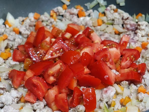 等絞肉變色出油，接著放入番茄丁，番茄要和油一起炒會釋出比較多營養。