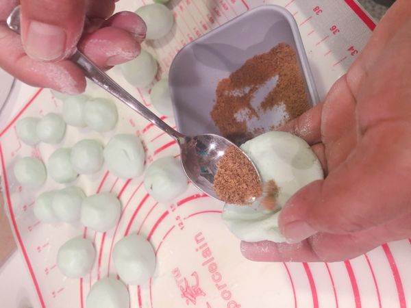 將已調好的材料，曲適當大小米糰，捏扁放入適量椰糖，收口包起來戳成圓形