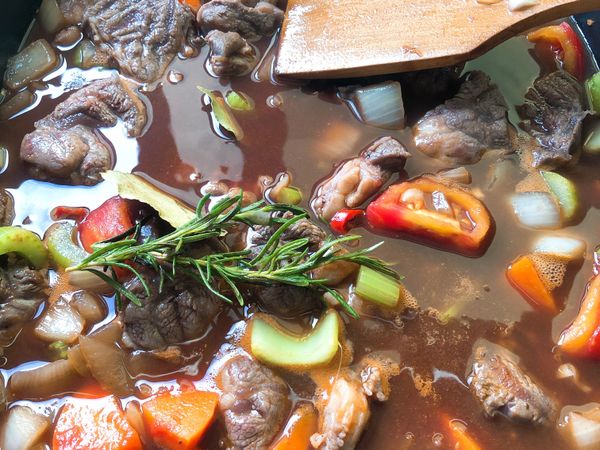 這時候加入紅酒、番茄糊、雞高湯和月桂葉、迷蝶香～均勻的拌一下！喜愛辣的人，請放入整條小辣椒一起小火燉煮30分鐘！