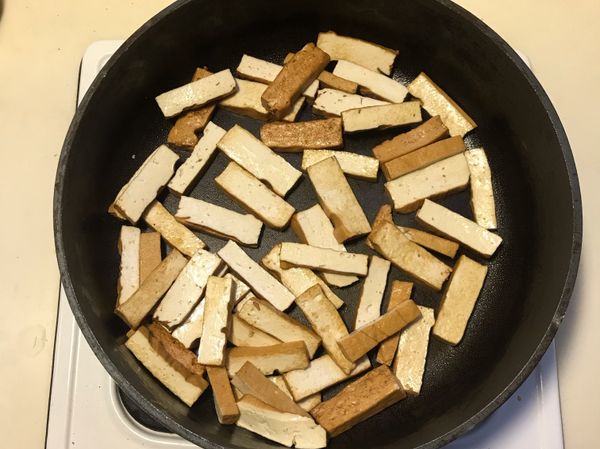 熱鍋後加油及豆乾，煸至略呈金黃