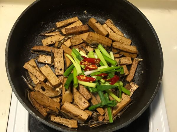 炒至沒有湯汁時加些許糖炒勻後，加入辣椒及蔥段拌炒