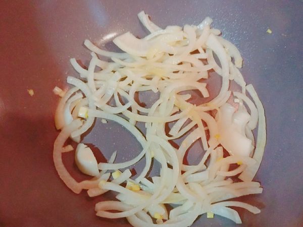 開大火，加入一點橄欖油，等油熱了以後倒入洋蔥絲炒。直到洋蔥變色。