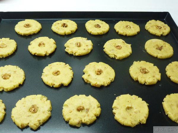 放入烤盤，壓成圓餅狀，中間用手指壓個小窩，核桃剝成小塊狀，壓放在小窩內。