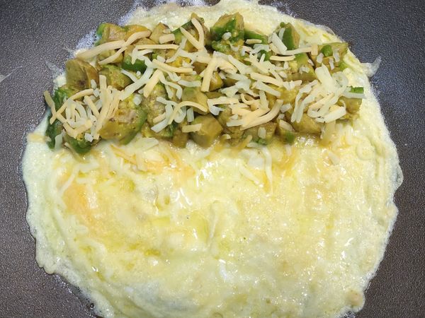 奶油下鍋熱鍋冒煙時轉最小火，下蛋液慢煎至中心已有稍凝固不太會滑動時，隨意的放上起司絲、酪梨。

我是只在半邊灑一層起司絲再放酪梨，接著再灑起司絲，另一邊的蛋片直接翻過去這樣比較好翻。