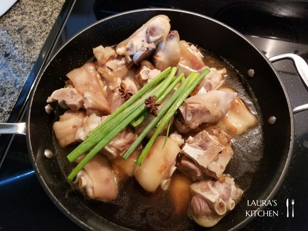 倒入醬油、米酒，再加一些水讓醬汁醃過豬腳，最後灑上一點白胡椒粉、加入八角、蔥綠，蓋上鍋蓋，大滾後轉中小火燉煮1.5~2小時