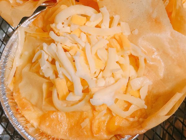 在蛋撻上灑上適量的起司絲，再以180度氣炸3分鐘，讓起司絲呈現焦黃狀，就完成囉