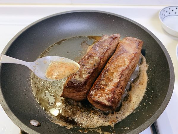 上色完成後，轉中小火，用湯匙將奶油不斷均勻淋上牛小排，肉也要不斷轉面，手指按壓牛小排確認熟度。