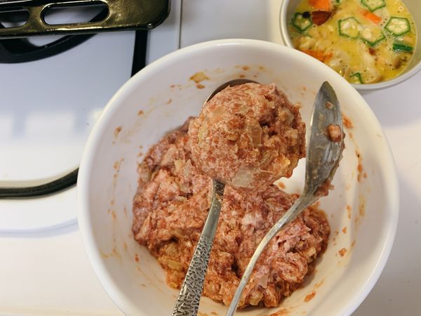 用兩支湯匙將肉塑成圓球狀放入未開火的平底鍋中。