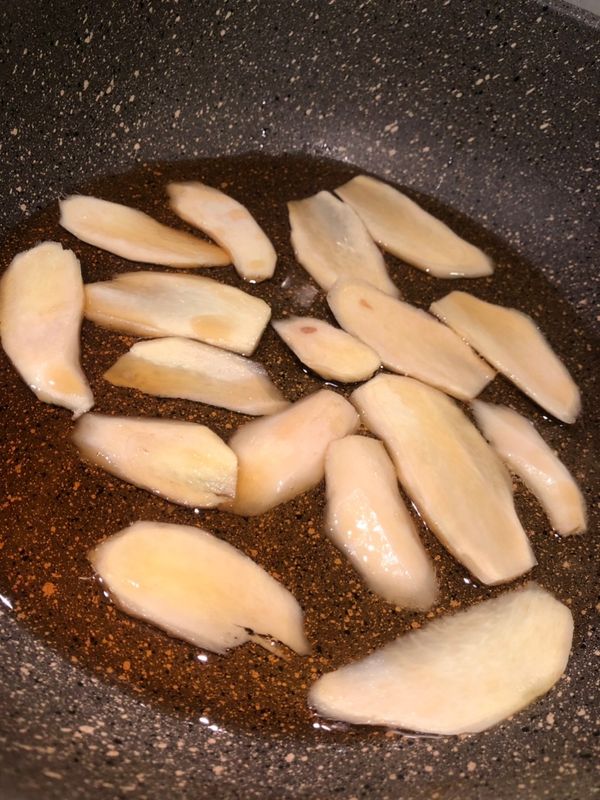 炒鍋放入麻油, 薑片, 用小火慢慢煸至薑片縮小捲曲, 約6-7分鐘, 再取出薑片備用.