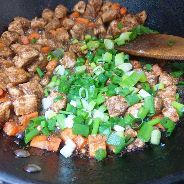 將醃置過的雞丁加入，並將剩餘的沙茶醬全部加入，翻炒至雞丁全熟透，最後加入蔥花快炒。