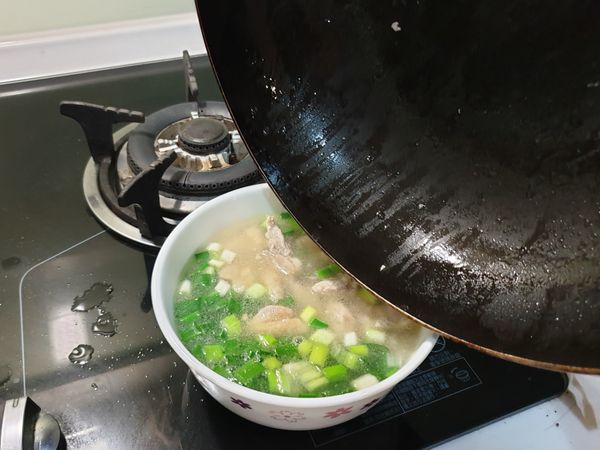 加鹽、胡椒調味後，把雞湯倒進蔥碗裡