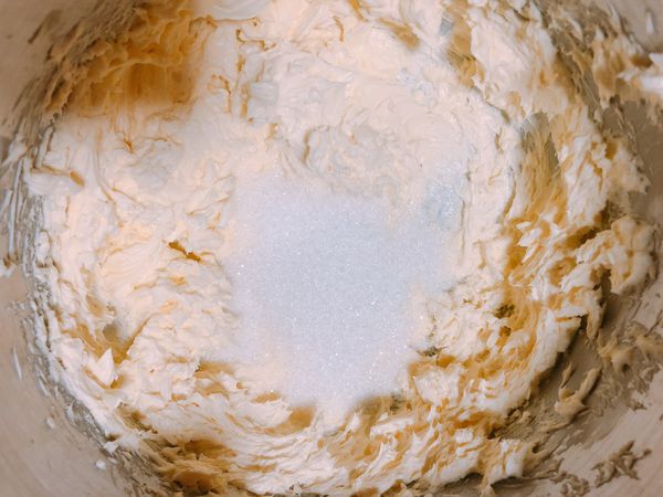 乳酪打散後，加入細砂糖，用攪拌機繼續攪拌至蛋糕體變柔順