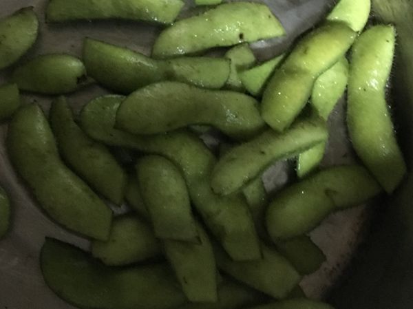 先將生毛豆用水洗兩三次泡點鹽水，泡滿水過一些時間再來處理，用剪刀剪掉後面的尾巴如圖