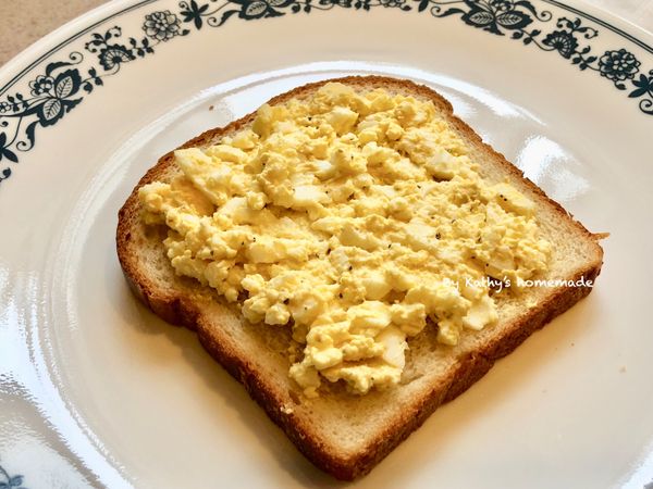 吐司麵包平舖在盤裡，塗抹雞蛋沙拉。