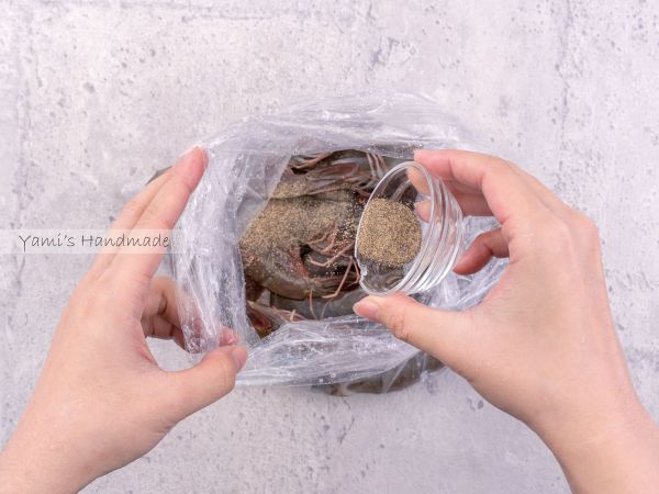 取一個塑膠袋或容器，放入已處理好的蝦子，加入黑胡椒粉