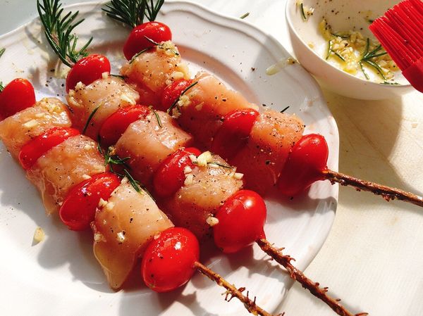 以迷迭香枝串起雞肉及小番茄，然後雙面刷上調好味的橄欖油