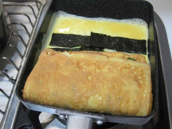 第三份蛋液下鍋後直接鋪上海苔，即將第三步驟完成的多層次蛋對折後靠一邊放入。