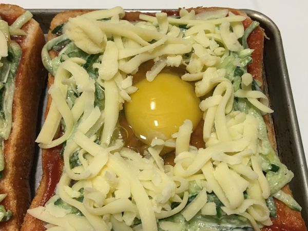 吐司中間用湯匙稍微壓一下，在中間凹槽打一顆蛋，吐司上層再鋪上一層起司絲⋯⋯