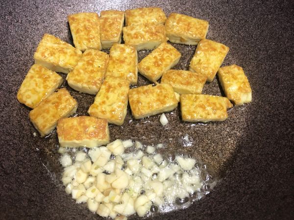 豆腐雙面都煎至焦香後，維持小火，加入蒜末煎出香氣後跟豆腐一起輕輕拌炒。