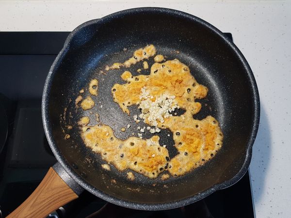 炒至鹹蛋黃全部起泡後，加入大蒜，拌炒均勻。