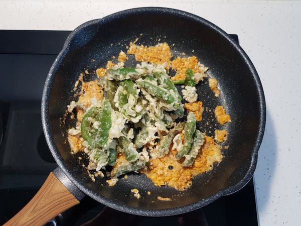 加入炸過的糯米椒，翻炒至糯米椒表面均勻沾上鹹蛋黃。