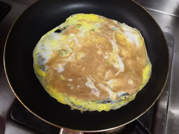 蓋上鍋蓋，小火烘餅皮，數十秒後表面凝固，轉大火約十秒，烘到餅皮周圍翹起，不怕燙話捏著餅皮一角，將鍋鏟鏟入餅皮中心翻面，怕的話放盤子上翻面