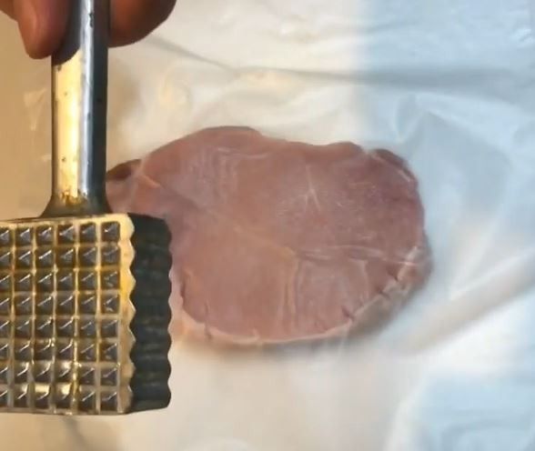 以保鮮膜或塑膠袋覆蓋豬排表面，避免肉汁亂噴，以肉槌拍鬆豬排，正反兩面都要