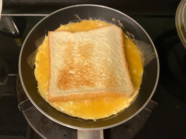 開蓋後確認熟度，蛋略冒泡就可把吐司放入，此時可離火，用筷子把蛋邊緣走過一遍，即可用煎匙將吐司翻面