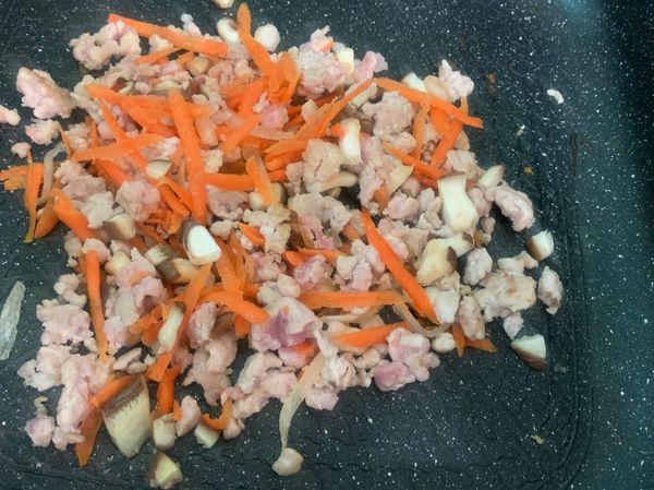 紅蘿蔔刨絲、香菇切粒，與絞肉拌炒，加入鹽巴調味
