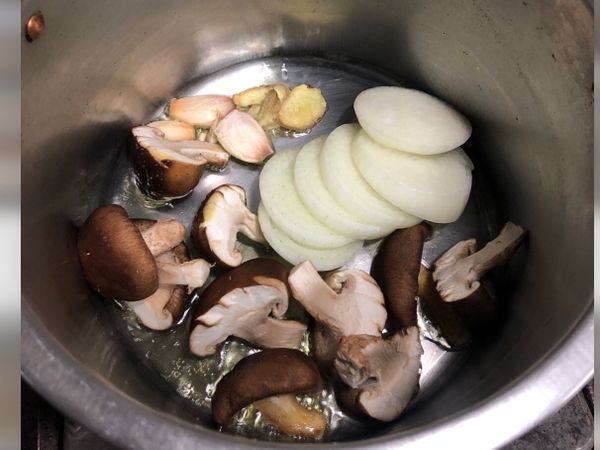 取一深鍋，小火，放少許油，爆香薑蒜、香菇及洋蔥。