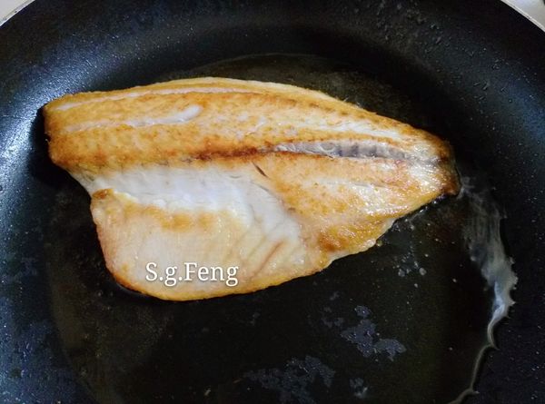 23.再將鱸魚片翻面，續煎約5分鐘，煎至兩面金黃上色恰恰即可關火。