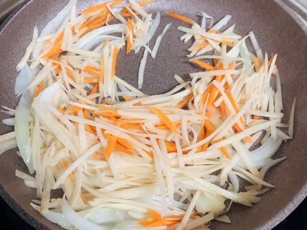 洋蔥略微軟化後倒入馬鈴薯及紅蘿蔔拌炒，加入少許水略為燜煮，切記不可以太久否則馬鈴薯太熟後就會失去清脆的口感