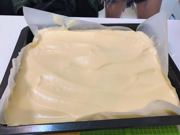 把翻拌好的麵糊倒入烤盤中 
用刮到抹平 振出氣泡