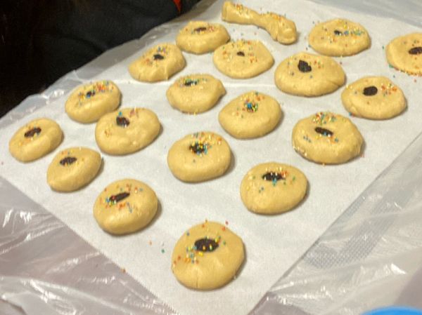 將曲奇團分成約25等份，每一份搓成圓形球狀，按扁，加入自己喜歡的裝飾，例如：朱古力、提子乾、糖粉等......