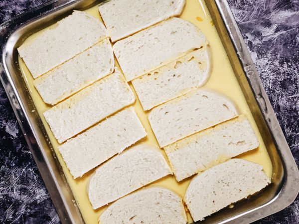 將蛋液倒入有深度的容器內，讓饅頭浸泡其中，使兩面都完整吸附蛋汁。饅頭不像法國吐司需要滴落多餘蛋液，因為麵體紮實不會像吐司那般容易軟爛。可以前一晚先泡好，隔天直接使用。