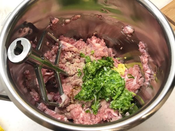 豬肉餡放上攪拌機以槳狀頭攪打，攪打的過程中慢慢加入食材的100g水分(俗稱打水)，水分會被肉泥吸收進去，這樣讓肉餡會更多汁、更好吃，之後加入食材內的調味料繼續攪打，要把絞肉打出筋性來，絞肉會變得有黏性。