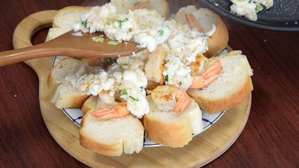 每片法國麵包放上鳳尾蝦仁，再鋪上炒鮮奶灑上黑胡椒粉。