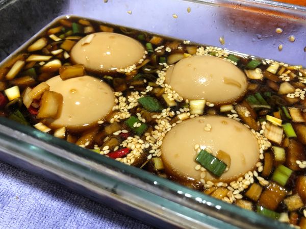 把醃料滷汁（醬油、砂糖、開水）和辛香料（青蔥、洋蔥🧅、辣椒🌶️、蒜泥🧄、芝麻粒、芝麻油）混合均勻，再把剝好的雞蛋🥚放入滷汁中，送進冰箱冷藏隔夜。