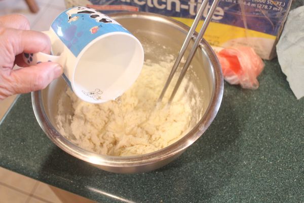 麵粉加入蛋清、鹽，慢慢倒入60-70℃的溫水，邊倒邊拌，將麵粉拌成絮狀。