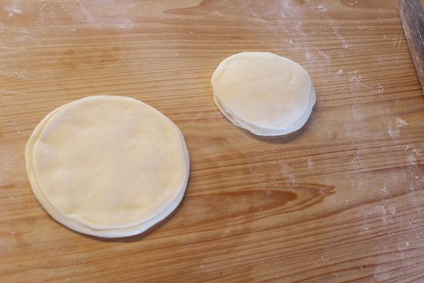 將整疊麵皮用手指慢慢捏平，壓成更寬扁的麵皮。