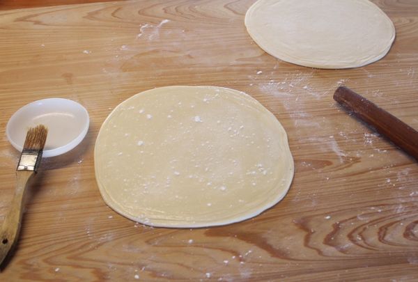 兩疊都桿好後，一疊表面抹上油脂，灑上麵粉，將另外一疊也蓋上。如果講究一點，可以拿個比麵皮稍小的大盤子倒蓋在麵皮上，切除邊邊，這樣大小可以一致，而且邊邊比較不容易有較厚的折皮。