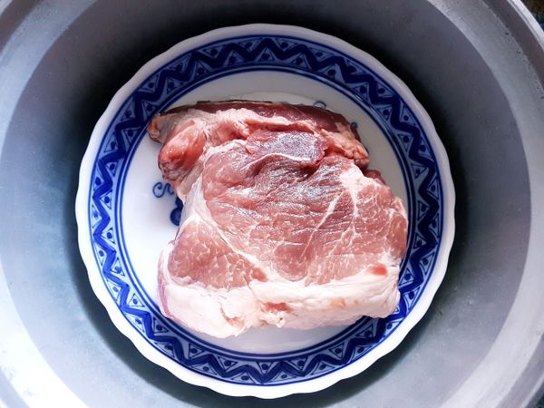 電鍋加入1.5杯量米杯水，放上沖孔蒸盤再將步驟1豬肉連餐盤擺入。