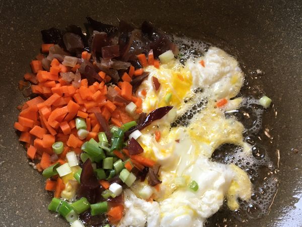 放入紅蘿蔔丁、木耳丁、一半的蔥花，拌勻炒香⋯