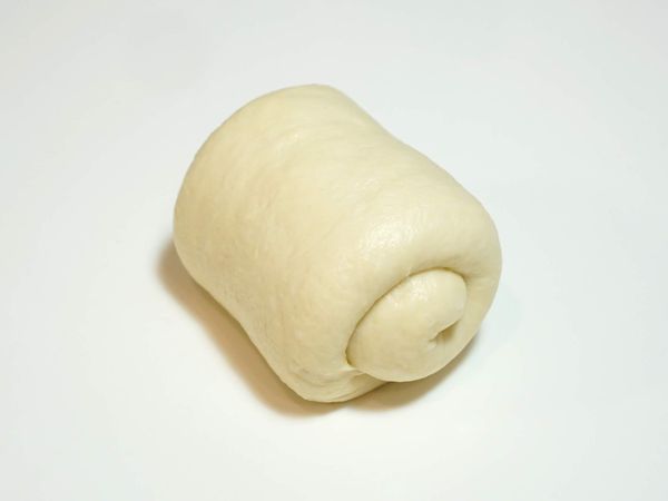 將麵團取出分切成2等份，將麵團擀成長橢圓，先由兩側向內對折後再捲起來。